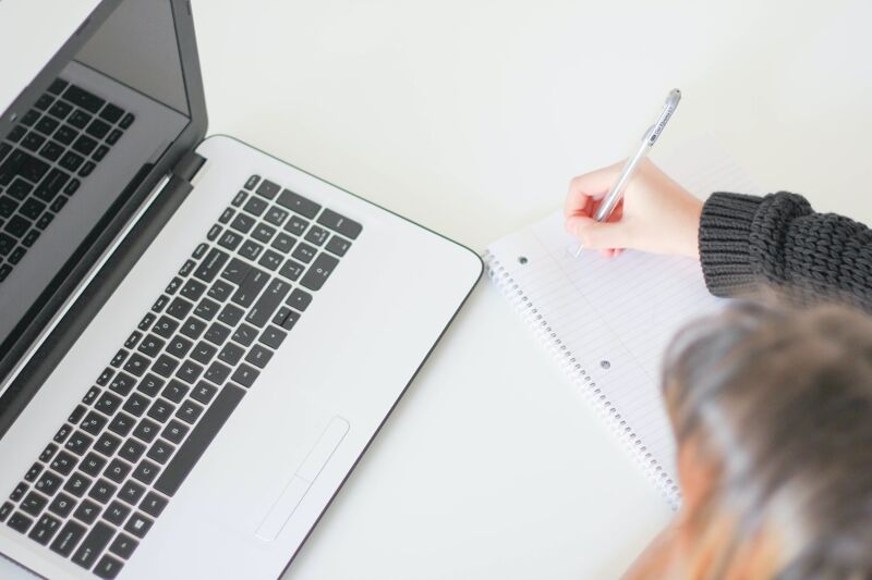 Jeune femme qui écrit une checklist à côté d’un ordinateur portable Jeune femme qui écrit une checklist à côté d’un ordinateur portable
